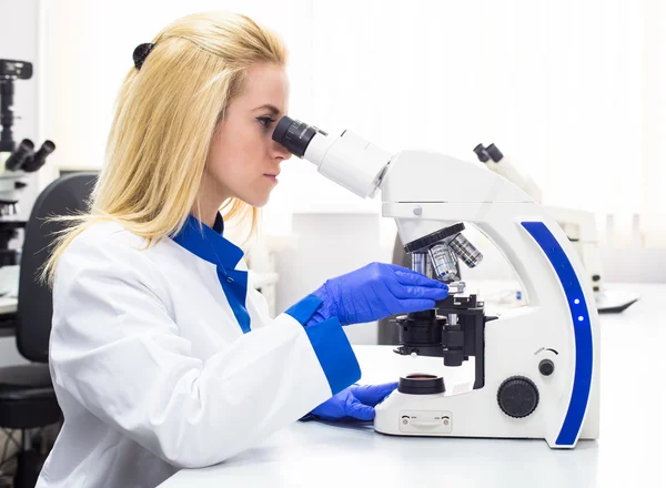 Ιατρική εργαζόμενο, εξετάζει σε ένα μικροσκόπιο — Φωτογραφία Αρχείου