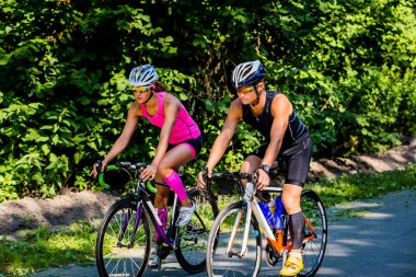 Young pair of professional cyclists riding on the road 