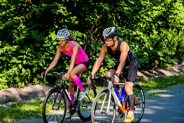 Young pair of professional cyclists riding on the road — 图库照片