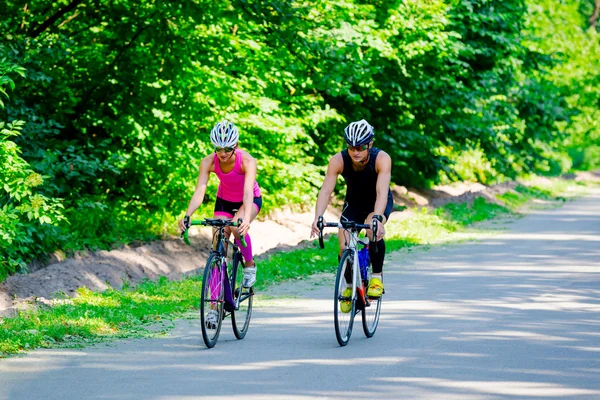 Young pair of professional cyclists riding on the road — Stok fotoğraf