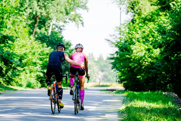 Молодая пара профессиональных велосипедистов, едущих вместе по дороге — стоковое фото