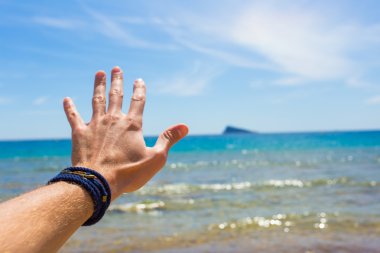Closeup picture of mans hand on sea background