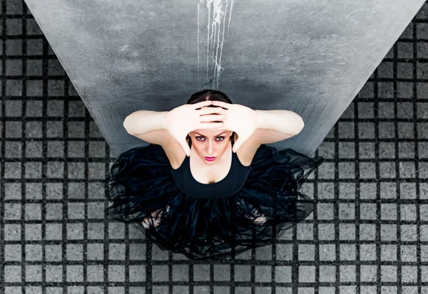 Ballerina ser upp mot den grå plattor och plattor av betong — Stockfoto