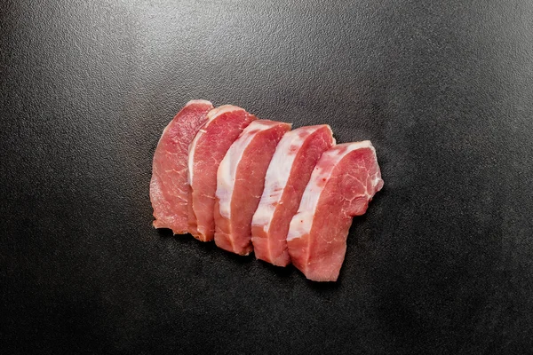 Filetes de carne cruda sobre fondo negro texturizado — Foto de Stock