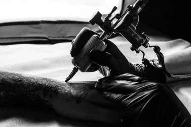 Tattooist makes tattoo on clients arm in bw clipart