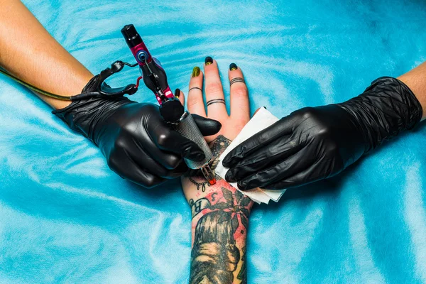 Tattooist draws orange paint on clients tattoo — Stock Photo, Image