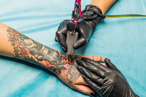 Татуировщик демонстрирует процесс татуировки под рукой — стоковое фото