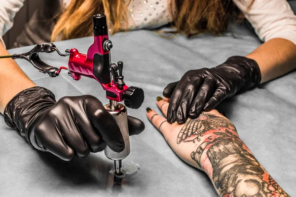 Tattooist take paint for tattoo which draws a girl — Stock Photo, Image