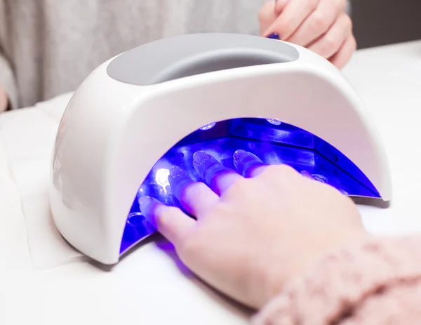 Manicure in process using Uv lamp for nails