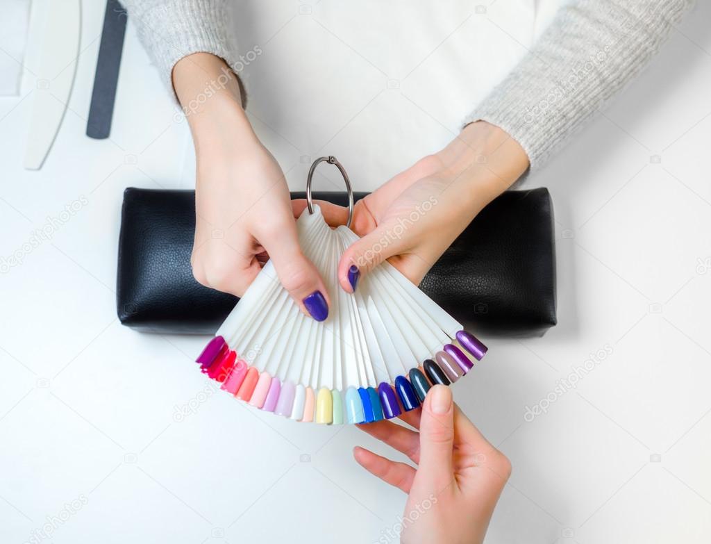 Girl look dark palette of varnish for nail polish