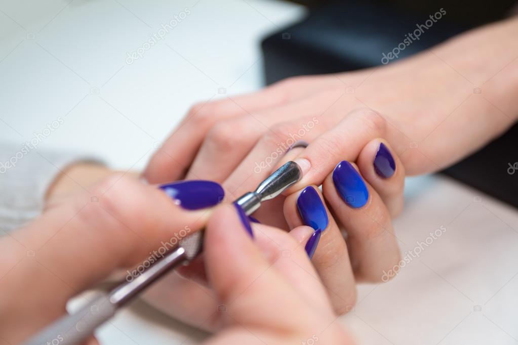 Woman in salon receiving manicure by beautician