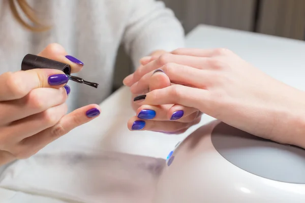 Beautician paints nails woman client in the salon