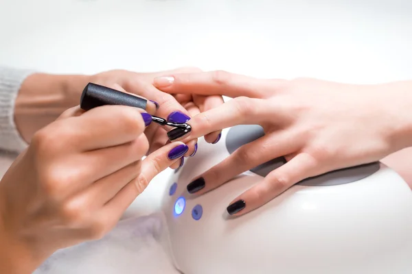 Manicurist applies nail gel polish middle finger — Stock Fotó