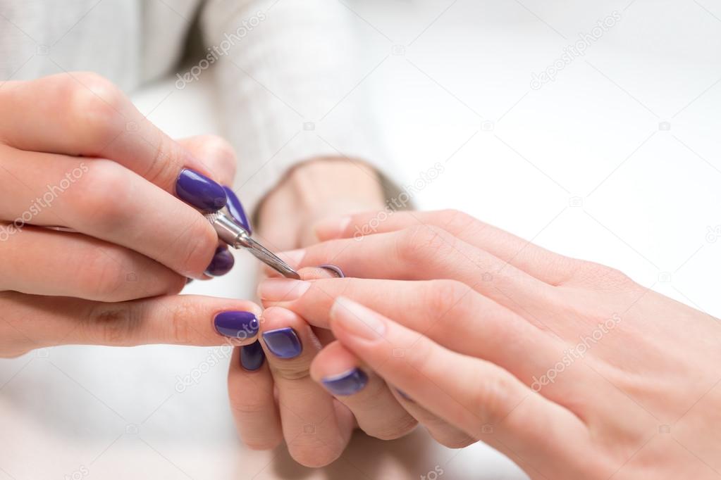 Manicurist removing cuticle from ring finger girl