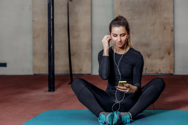 Attraente donna fitness con lettore mp3 sul tappeto — Foto Stock