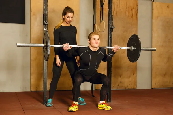 Personal Trainer unterstützt bei der Kniebeuge-Übung — Stockfoto