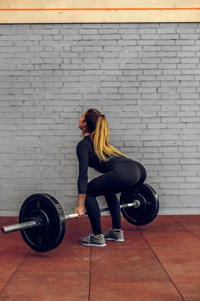 Молода жінка піднімає важкі ваги в спортзалі — стокове фото