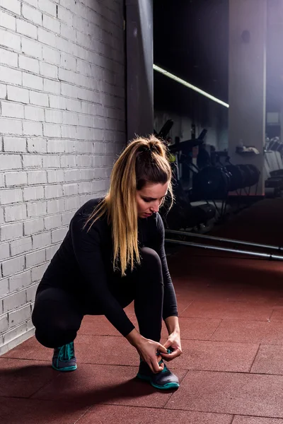 Фітнес дівчина зав'язує шнурки в спортзалі — стокове фото