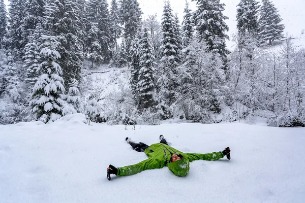 Jovem deitado na neve na floresta — Fotografia de Stock