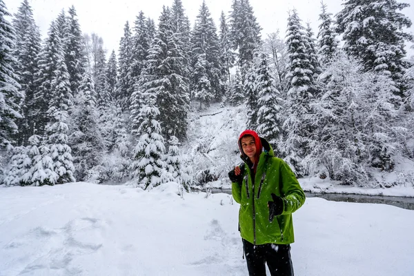 Jeune homme en bois d'hiver montre les pouces vers le haut — Photo