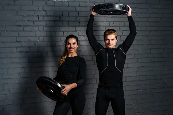 Strong man an sporty woman in gym — Stock Photo, Image