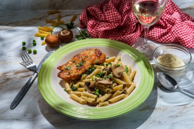 İtalyan usulü makarna, ıspanak mantarlı ve bezelyeli ızgara tavuk göğsü, bir bardak beyaz şarap ve maydanozlu garnitür.
