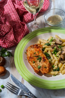 İtalyan usulü makarna, ıspanak mantarlı ve bezelyeli ızgara tavuk göğsü, bir bardak beyaz şarap ve maydanozlu garnitür.