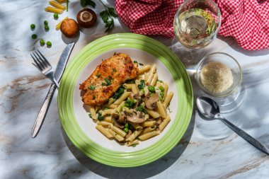 İtalyan usulü makarna, ıspanak mantarlı ve bezelyeli ızgara tavuk göğsü, bir bardak beyaz şarap ve maydanozlu garnitür.
