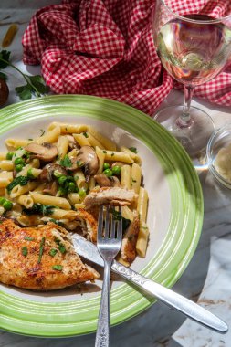 İtalyan usulü makarna, ıspanak mantarlı ve bezelyeli ızgara tavuk göğsü, bir bardak beyaz şarap ve maydanozlu garnitür.