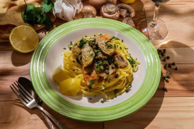 İtalyan tavuklu piccata linguine, mantarlı enginar kalbi ve kapari, bir bardak kuru beyaz şarapla eşleştirilmiş.