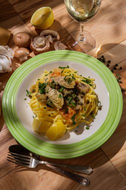 İtalyan tavuklu piccata linguine, mantarlı enginar kalbi ve kapari, bir bardak kuru beyaz şarapla eşleştirilmiş.