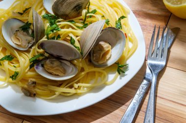Küçük boyunlu beyaz şarap, midye sosu ve maydanoz garnitürlü linguine.