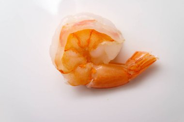 Yakın plan pişmiş kuyruklu pembe karides beyaz tabakta.