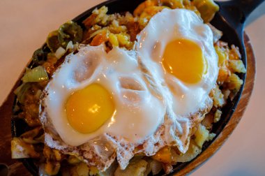 Tavada servis edilen iki kızarmış yumurta ve patates kızartması.