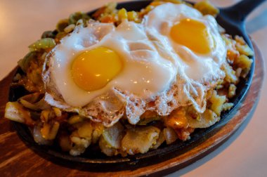 Tavada servis edilen iki kızarmış yumurta ve patates kızartması.