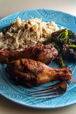 Otantik baharatlı Jamaika usulü tavuk budu hindistan cevizi pilavı ve bezelye ile servis edilir.