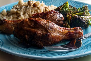 Otantik baharatlı Jamaika usulü tavuk budu hindistan cevizi pilavı ve bezelye ile servis edilir.