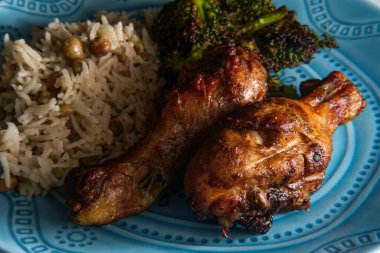 Otantik baharatlı Jamaika usulü tavuk budu hindistan cevizi pilavı ve bezelye ile servis edilir.