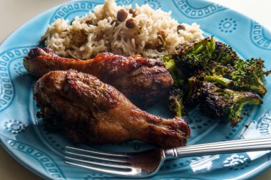 Authentic spicy Jamaican jerk chicken legs served with coconut rice and pigeon peas clipart