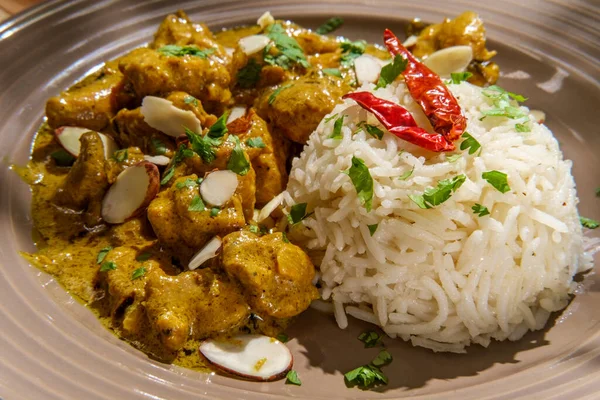 Indian chicken korma curry dinner with basmati rice and almonds