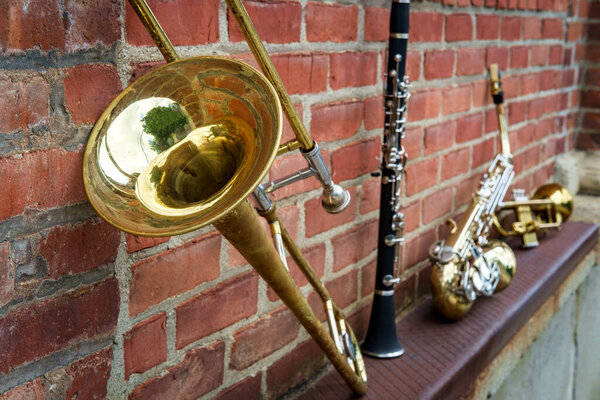 Musical instruments including trombone trumpet clarinet and saxophone on brick wall outside Jazz club