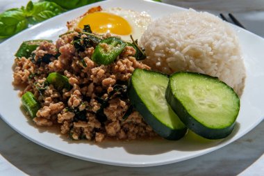 Phat Krapow Mu Sap aynı zamanda kızarmış Tayland fesleğeni domuz eti olarak da bilinir istiridye soslu beyaz pirinç ve kızarmış yumurtalı sunnyside ile servis edilir.