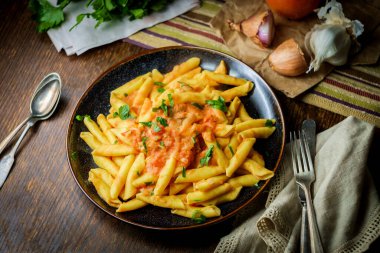 Kırsal ahşap mutfak masasında kremalı votka soslu makarna.