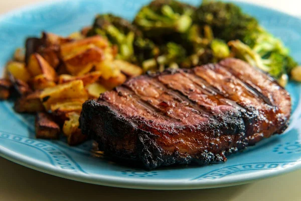 Kızarmış domuz pirzolası, yanında ızgara, yanında patates kızartması ve ızgara brokoli.