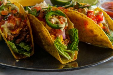 Meksika biftekli taco, kızarmış fasulye, tortilla cipsi ve çeşitli malzemeler.