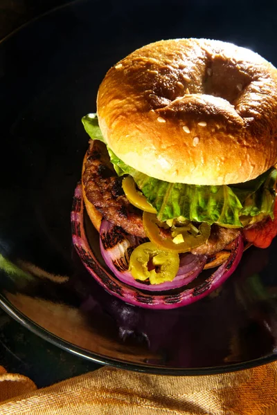 American food cheeseburger with pickled jalapeno peppers lettuce and grilled red onions