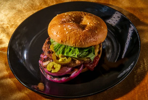 American food cheeseburger with pickled jalapeno peppers lettuce and grilled red onions