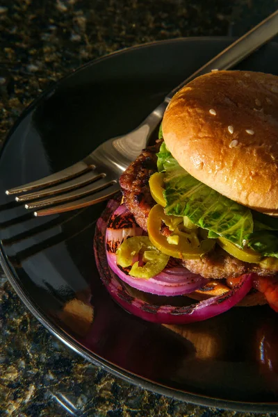 American food cheeseburger with pickled jalapeno peppers lettuce and grilled red onions