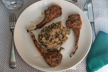 Peynirli mantarlı risotto ile marine edilmiş ızgara kuzu kaburgası.