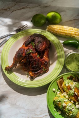 Peru usulü kavrulmuş yarım tavuk pollo a la brasa ile sokak mısırı ve yeşil sos.